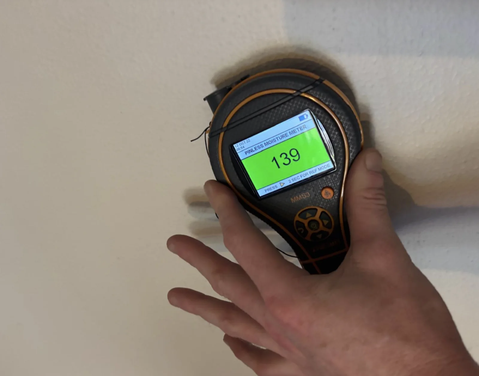 Moisture meter reading during a wall inspection